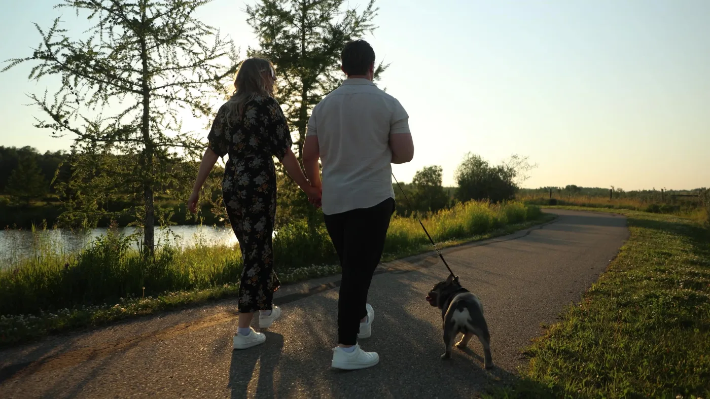 Couple walking their dog on a Valarosa path at golden hour